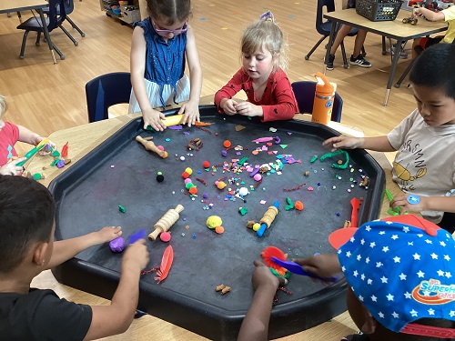 School age children working with playdough at the tuff tray 