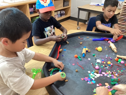 School age children working with playdough at the tuff tray 