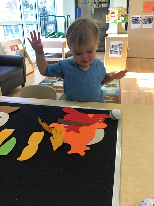 child engaging in play using a felt board to build their own scarecrow