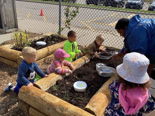 Children gathered around the garden bed
