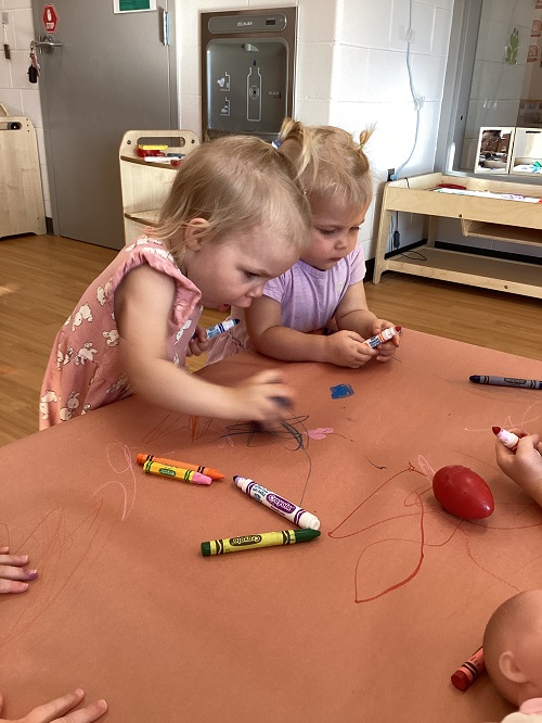 Toddler colouring at the table with crayons 