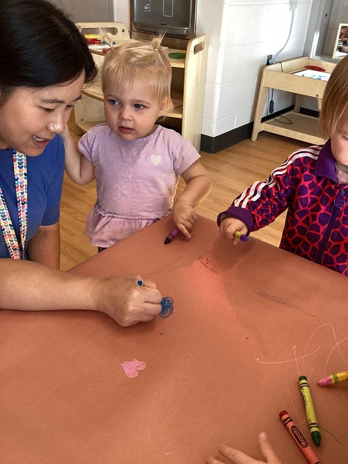 Toddler colouring at the table with crayons 