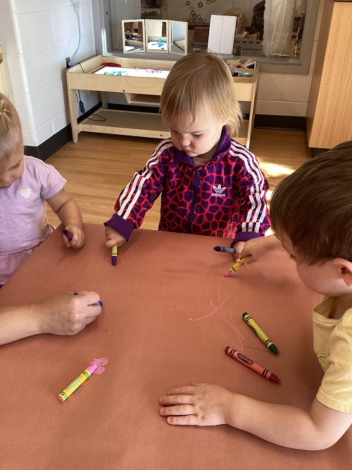 Toddler colouring at the table with crayons 