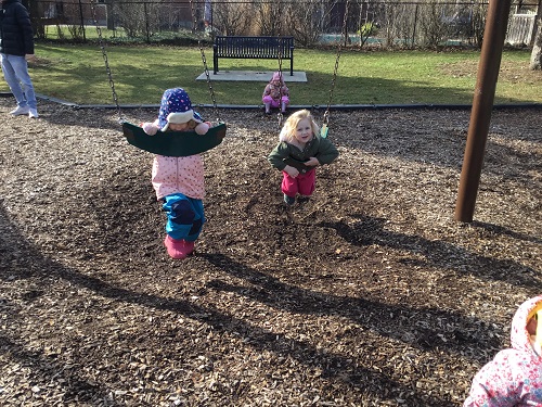 Children swinging on the swings on their bellies 