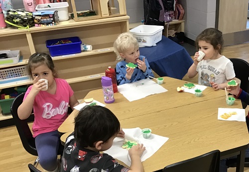 A group of children sitting around a table eating the cookies they made