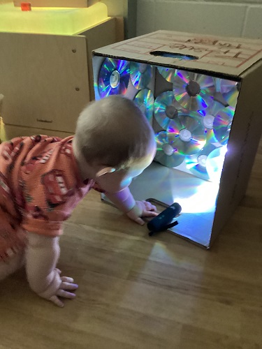 A child crawling to a box to check out the light reflecting 
