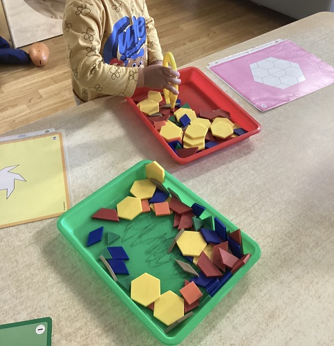 A child at a table using tongs to pick up shapes