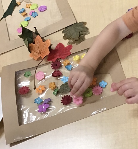 A child sitting at a table adding flowers to their artwork