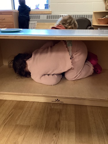 A child curled up on a shelf