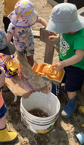 Children watching cars fall into a bucket of water off the ramp