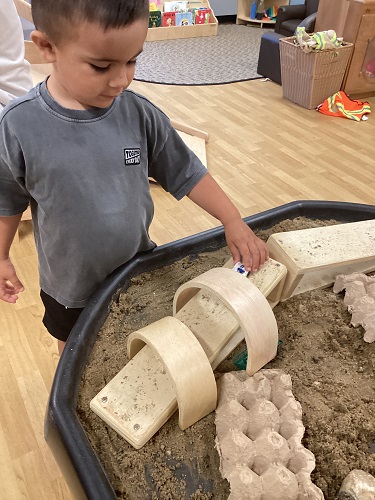 A child driving a car on a ramp in the sand