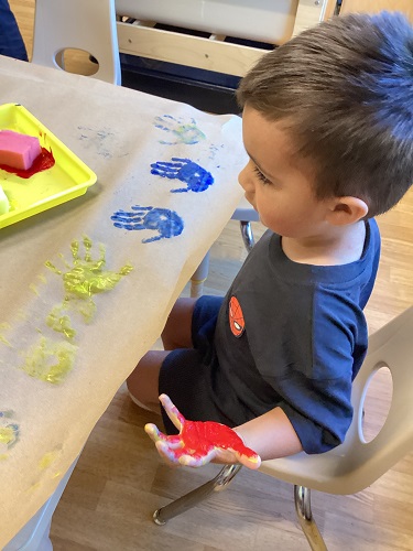 A child sitting at a table with paint on his hands