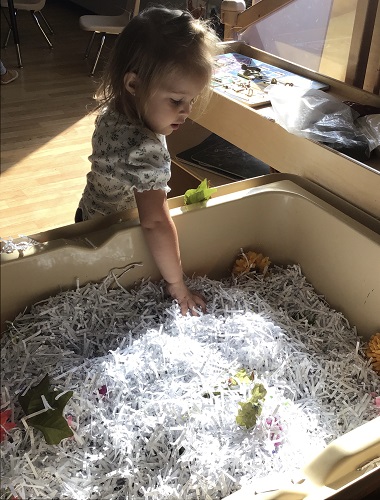 A child playing in a sensory bin filled with shredded paper