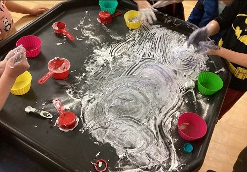 A tray covered in flour, bowls and measuring cups