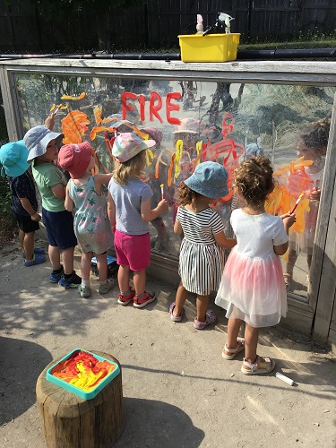 Children spraying paint off a mirror with water
