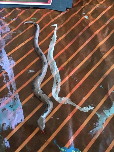 one toy snake with dried glue that was peeled off the snake beside