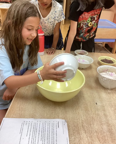 school-age child pouring ingredients into bowl