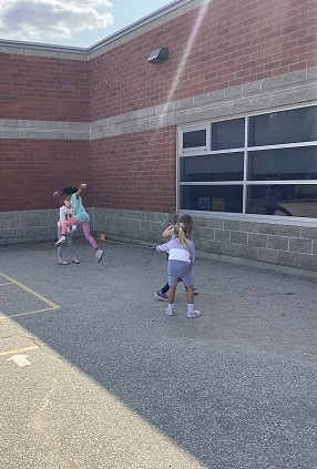Group of school-age girls playing skipping rope game 