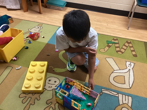 School-age boy with his structure of magent tiles