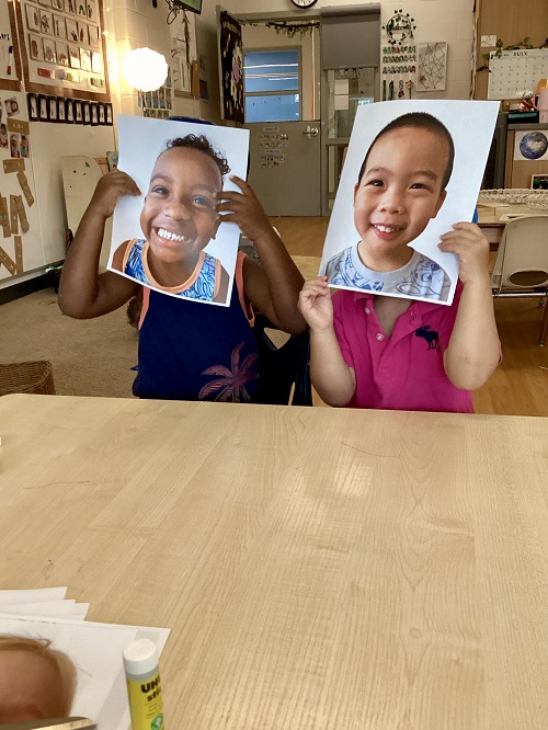Children displaying printed photos of themselves.