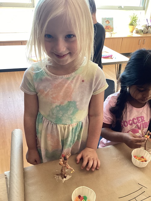 a school age child showing off their beaded tree