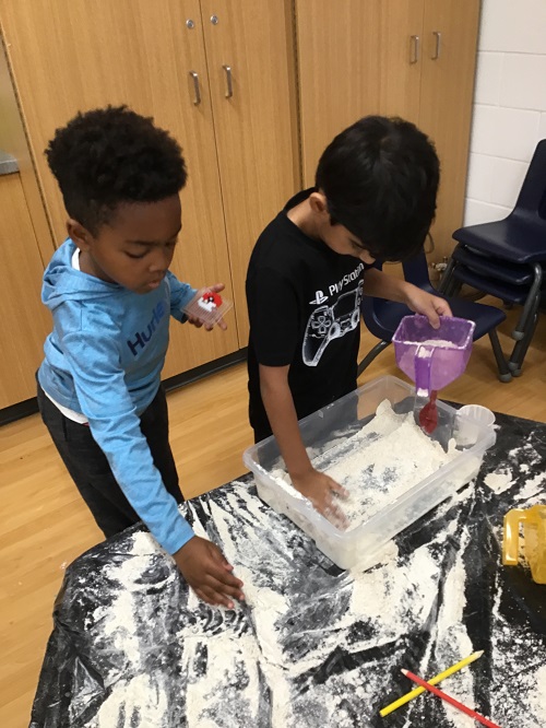 Two children working side-by-side as they create their stress balls