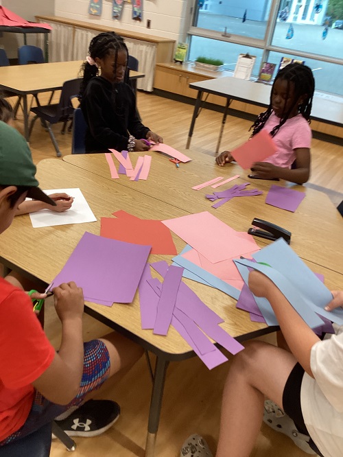 A group of children collaboratively creating a rainbow chain.