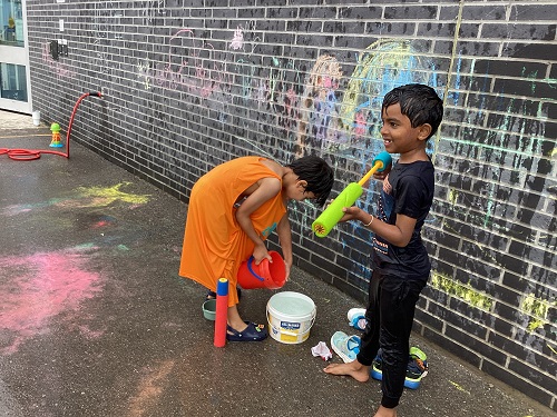 2 children engaging in water play outside.