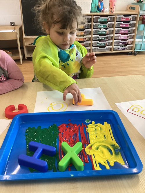 A child painting with letters.