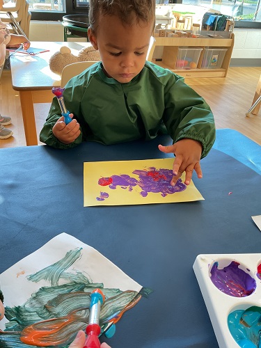 Child in green smock painting