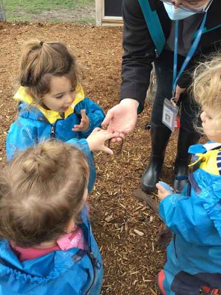 educator showing toddlers a worm