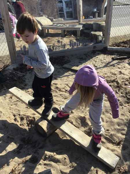 kids balancing on a plank resting on a log