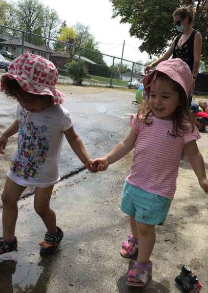 toddlers holding hands walking outside