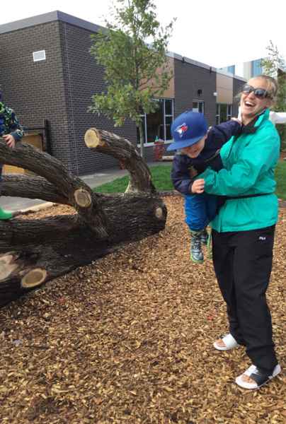 boy jumping off a log into educators arms