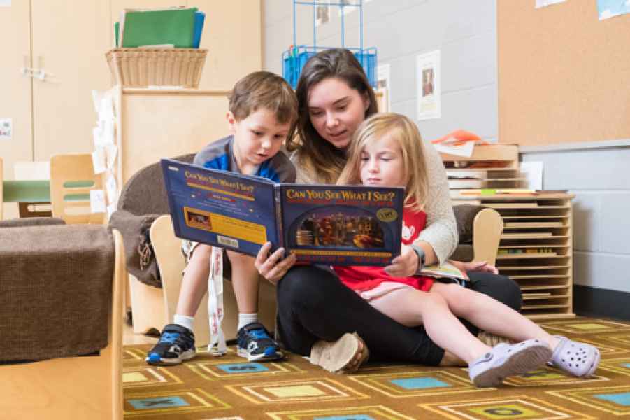 educator reading a book to preschoolers