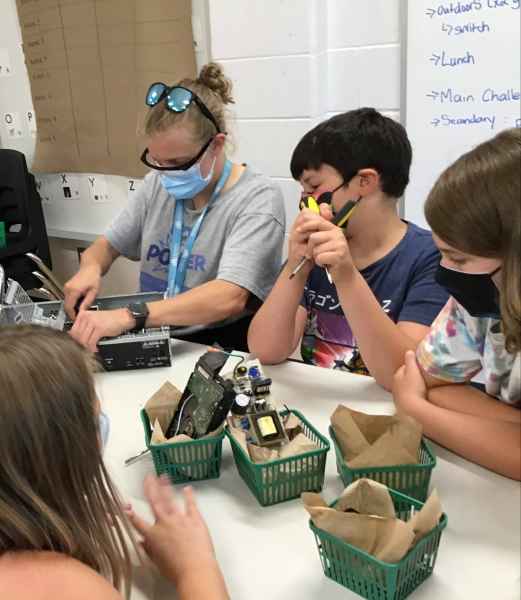 educator and campers pulling electronics apart and putting them back together
