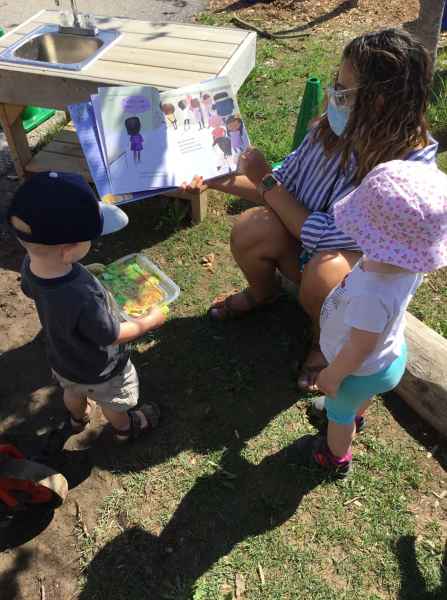 educator read a book to two children outside