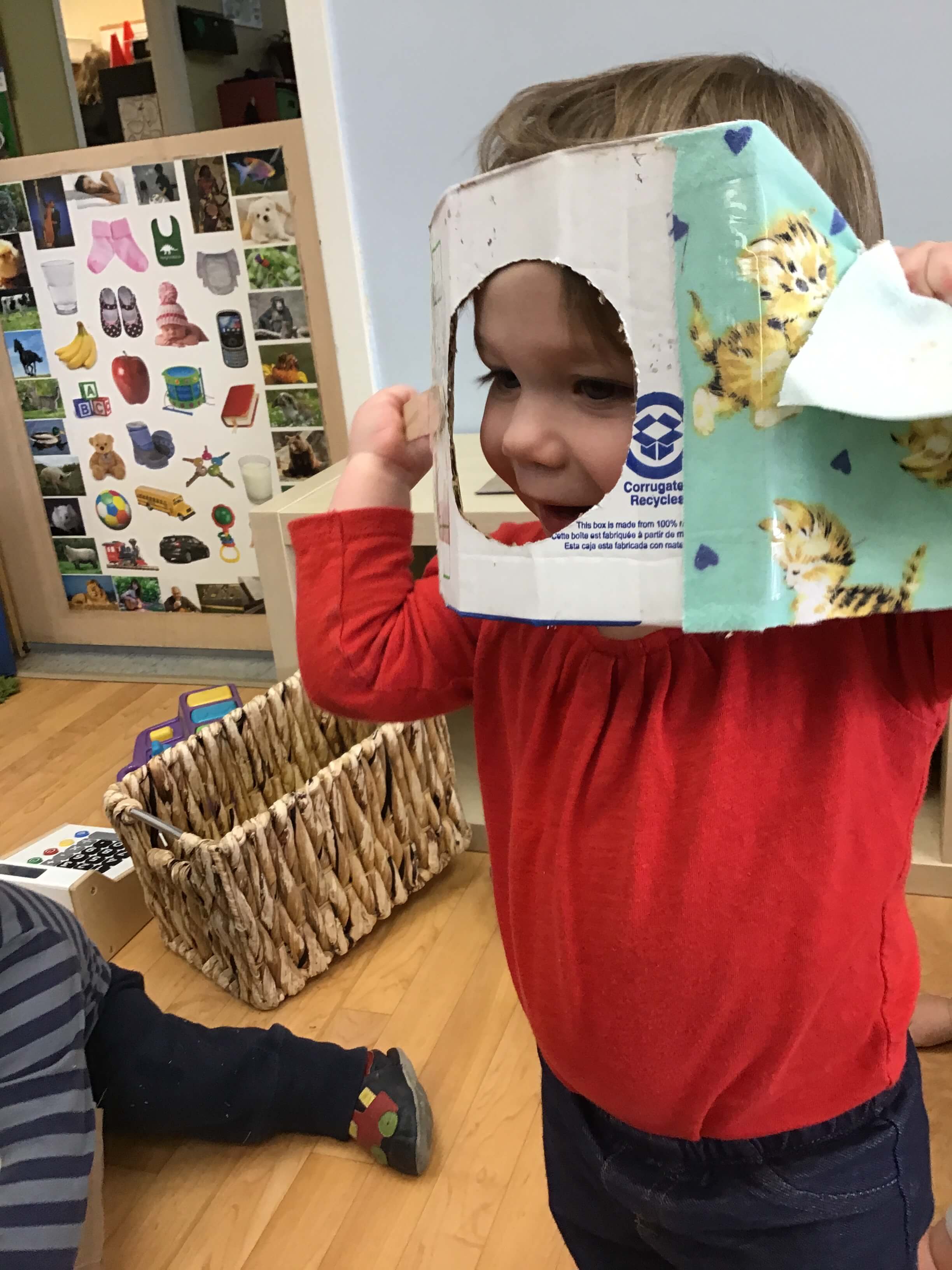 child hiding his face behind a box