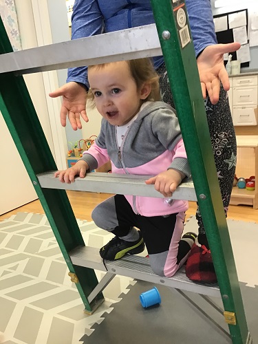 girl climbing a ladder with educator assistance