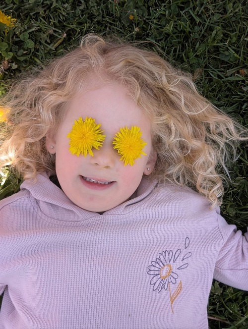 child posing for a picture with flowers over their eyes