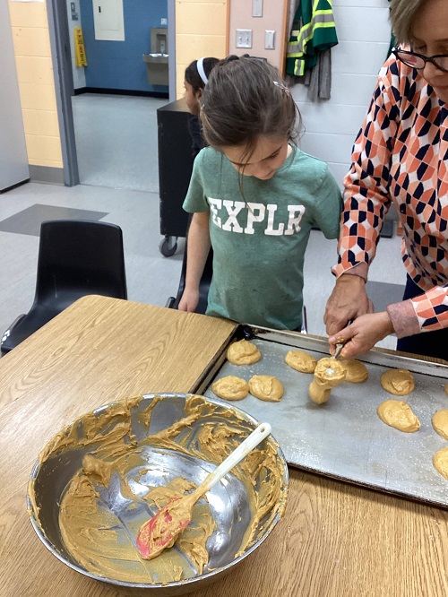 child placing cookies onto baking sheet
