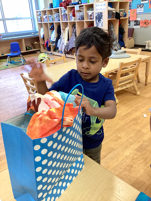 Child putting father's shirt in a gift bag. 