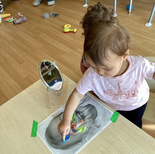 An infant finger painting on a photo of themselves