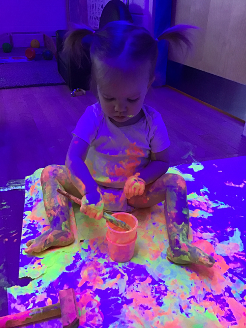 child getting messy painting on the floor