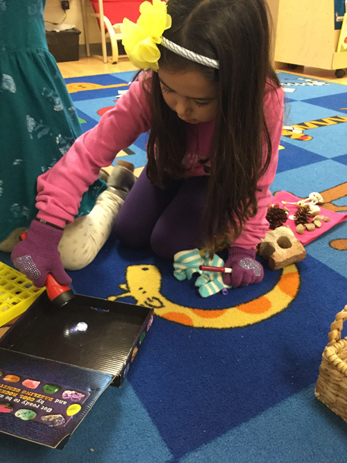 girl examining minerals with a flashlight