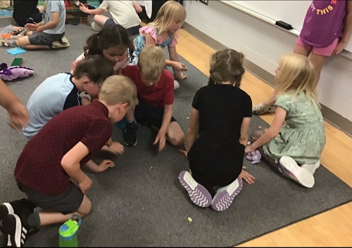 Children crouched on the floor looking for plastic gems
