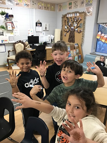 Four school aged children showing the Henna painted on their hands