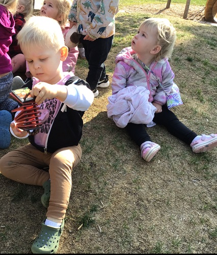 Toddlers sitting on a hill together